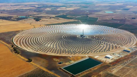 aerial view of a large circular power plant of solar panels in spain. there is the reflection of the sun in the the panels which produce renewable energy - environment concept