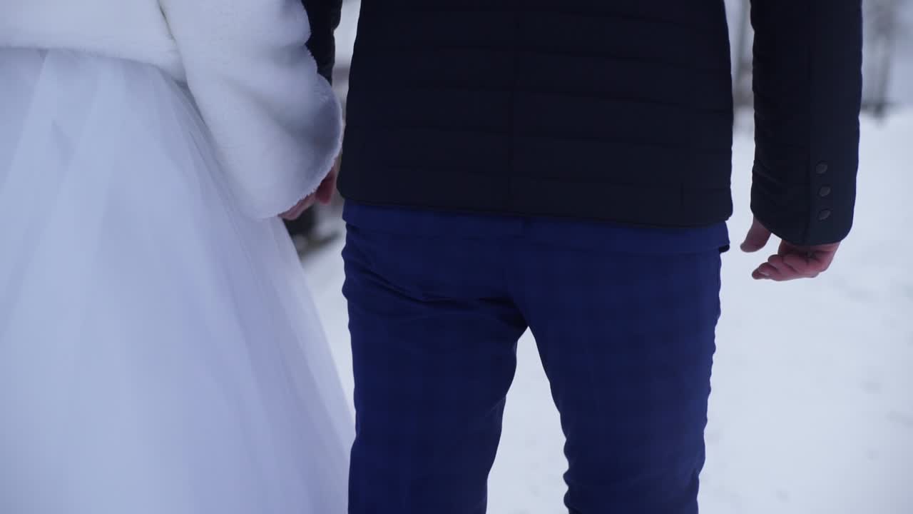 una pareja de bodas de invierno caminando en la nieve.