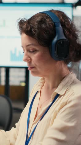 vertical video female executive consultant listening to songs on headphones at the workstation