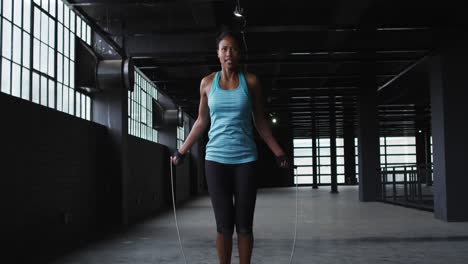 african american woman skipping the rope in an empty urban building