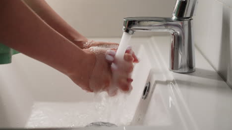 Una-Mujer-Con-Una-Cuidada-Manicura-Blanca-Se-Lava-Las-Manos-Con-Agua-Del-Grifo.