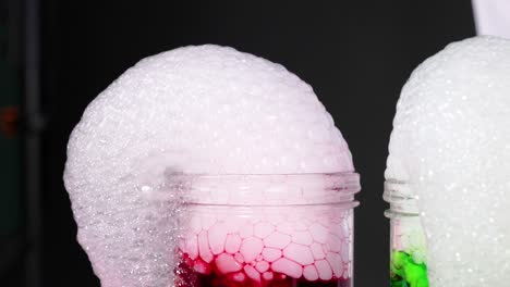 un vibrante experimento científico con hielo seco creando burbujas coloridas en líquidos rojos y verdes contra un fondo oscuro