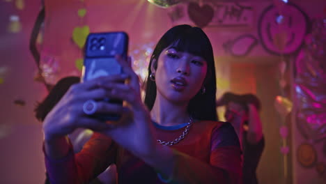 clubbing woman making selfie on smartphone at club party neon lights closeup