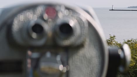 enfoque tirar de un binocular operado por una moneda a un faro en la distancia