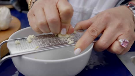 grating garlic into bowl on outside kitchen
