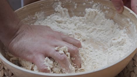 Chef-molds-the-pizza-dough-in-a-deep-plate,-on-a-wooden-table