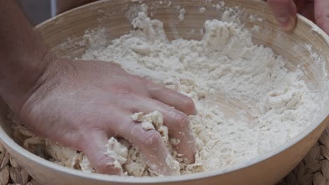 el chef moldea la masa de pizza en un plato hondo, sobre una mesa de madera