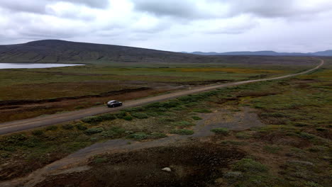 Aerial-tracking-shot-of-a-car-on-a-lonely-mountain-gravel-road-in-Iceland