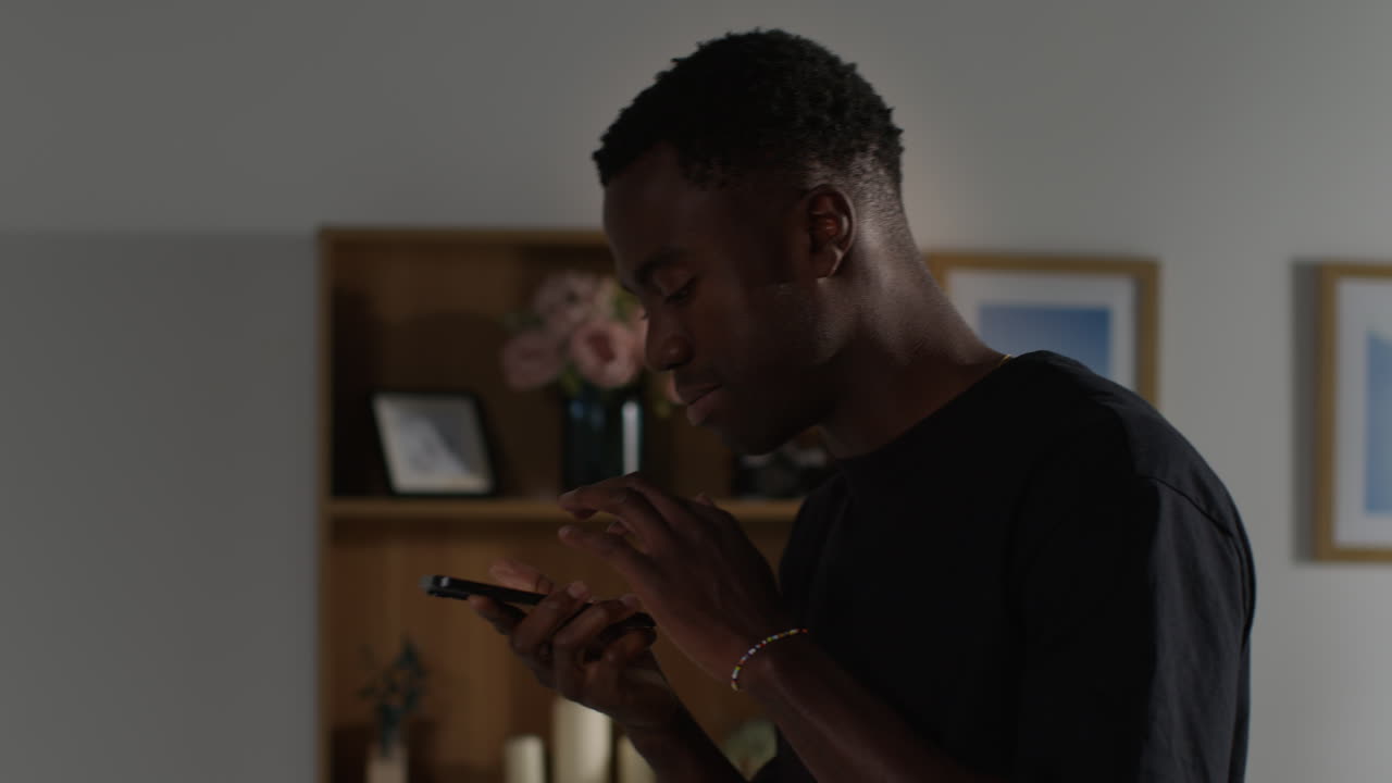 Angry Young Man Standing In Lounge At Home Having Argument And Ending Call On Mobile Phone