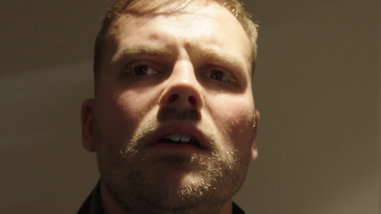 aggressiver mann verzerrt das gesicht und hält eine waffe close up he is talking to someone and is very angry.