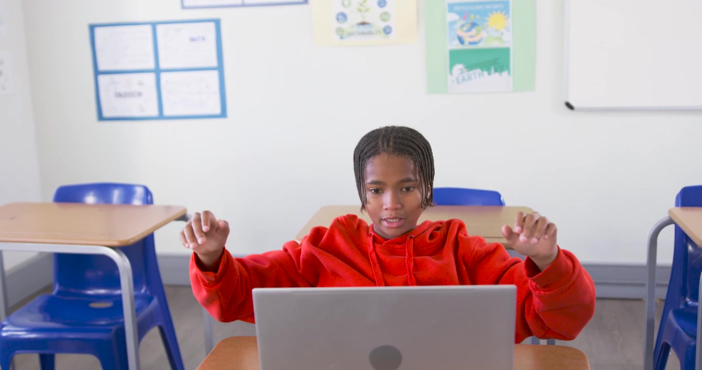 Adolescente afroamericano con felpa rossa che si stiracchia, apre il laptop, allinea lo schermo e appoggia la testa sulla scrivania
