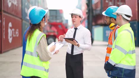 grupo de ingenieros, trabajadores y gerentes de pie en el contenedor del astillero. elevación de camiones y carretillas elevadoras detrás. importación, exportación de productos. transporte de fabricación y concepto de negocio global