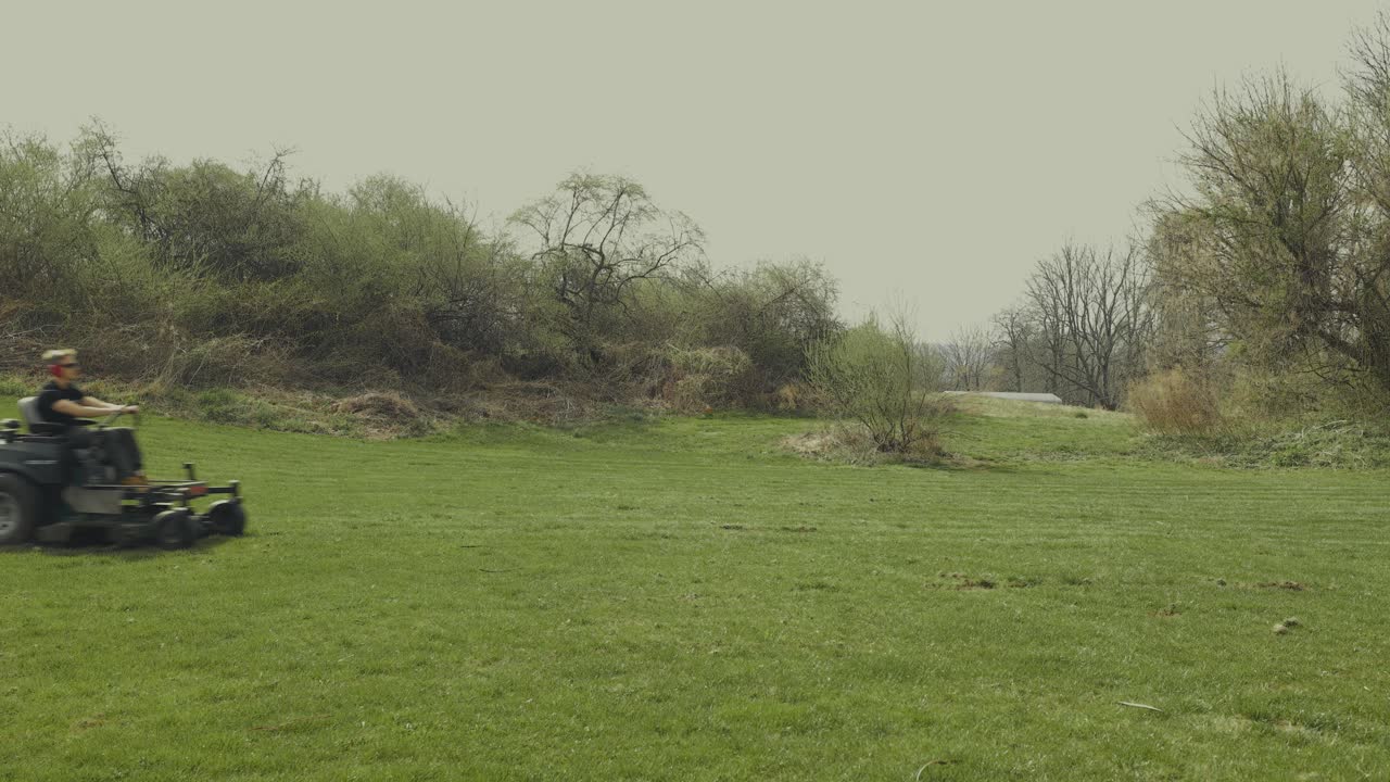 Homeowner operates a riding lawn mower to cut grass in the yard