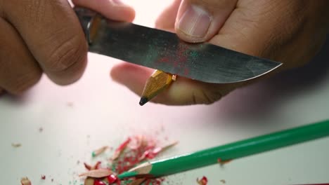 imágenes de manos afilando lentamente un lápiz y algunos lápices de colores con un cuchillo afilado