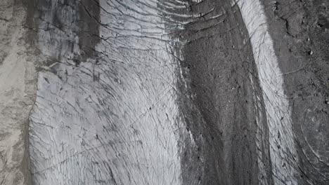 aerial view of the glacier ice sheet with cracks and fractures, pasterze glacier partly covered in debris, shrinking glacier at high tauern national park due to global warming, austria