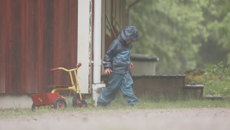 Cámara-Lenta---Un-Niño-Lindo-Juega-Con-Un-Tubo-De-Bajada-Bajo-Fuertes-Lluvias