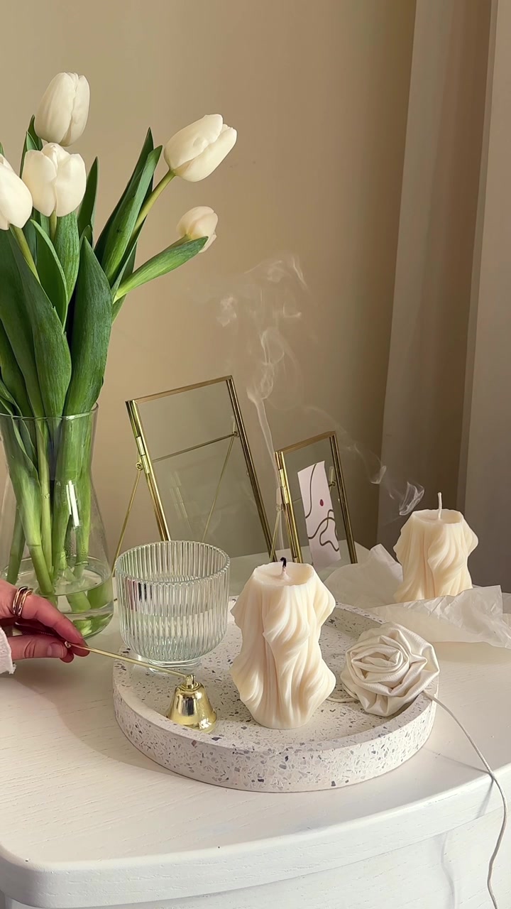 Main éteignant une bougie décorative avec un éteignoir en laiton