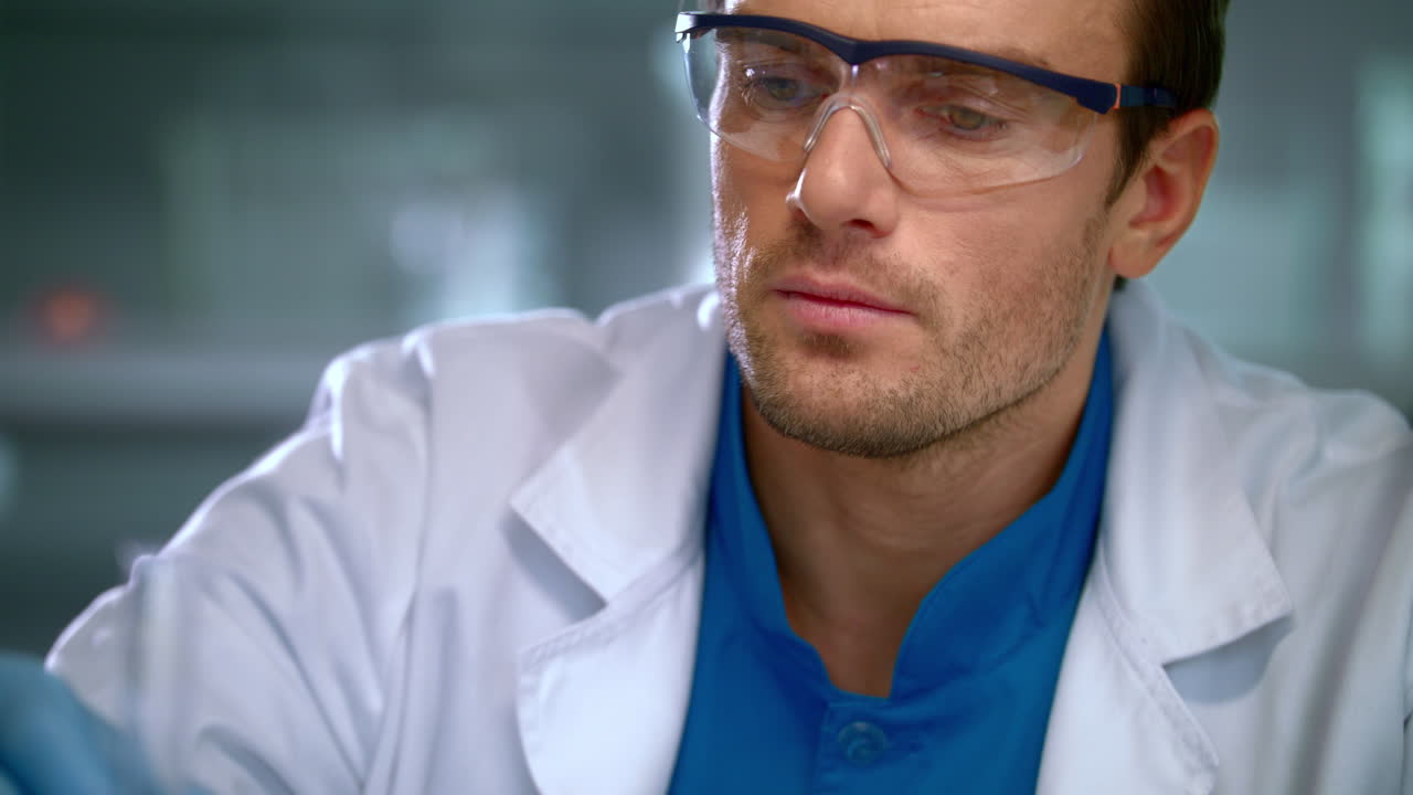 Male researcher studying liquid in glass flask at lab. Closeup of scientist man