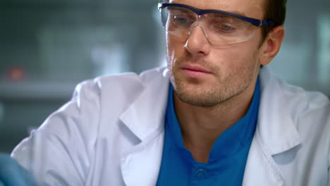 investigador masculino estudiando líquido en un frasco de vidrio en el laboratorio. primer plano del científico hombre