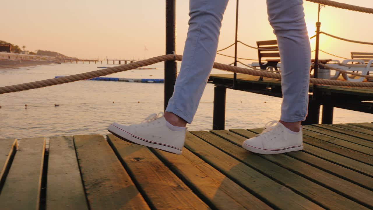 프레임에서 해가 바다 위로 떠오를 때 부두에서 아침 조깅 대신 다리만 보입니다.