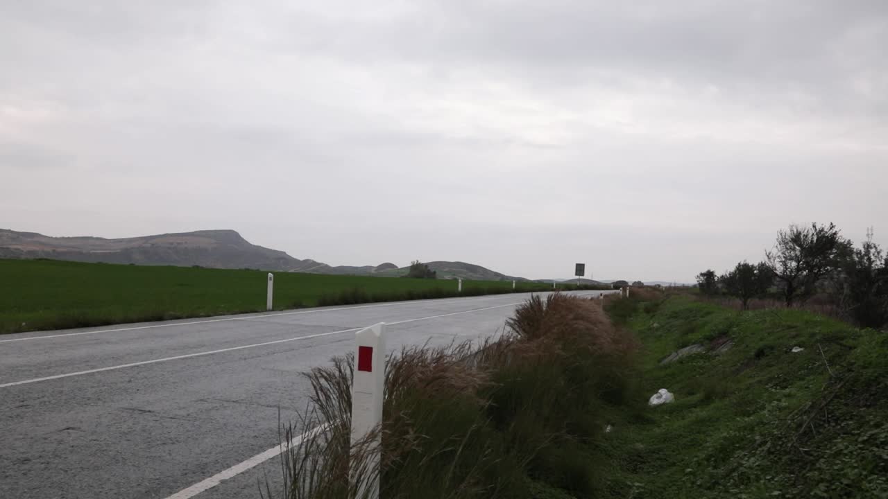 Two cars passing by a road in nature. The weather is moody and undertoned.