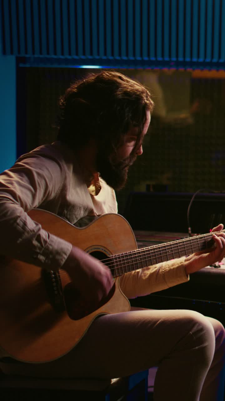 Hombre tocando la guitarra acústica en un estudio de grabación musical