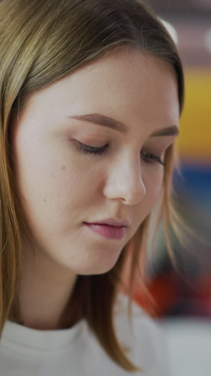 primer plano de una mujer enfocada y profundamente pensada mientras está sentada en un entorno comercial, el fondo colorido borroso presenta iluminación suave y espacios comerciales