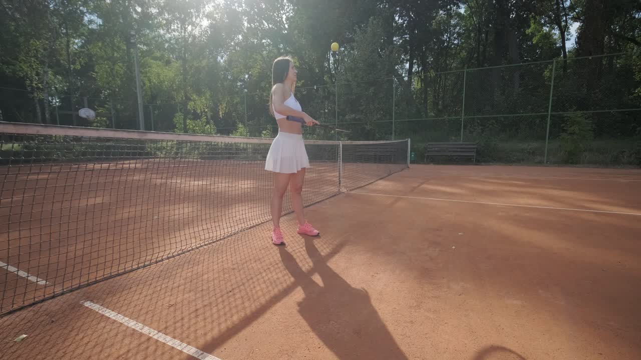 아름다운 테니스 소녀가 야외 코트에서 을 연습하고 있습니다.