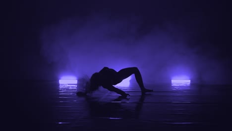 close-up of elegant actress in black outfit performing modern contemporary dance in darkness of studio
