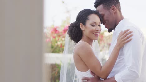 happy married african american couple embracing and wearing wedding clothes