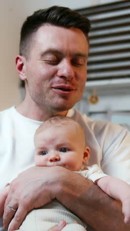 man kissing a newborn baby on the head. father is holding a tiny kid showing him all the love. vertical video