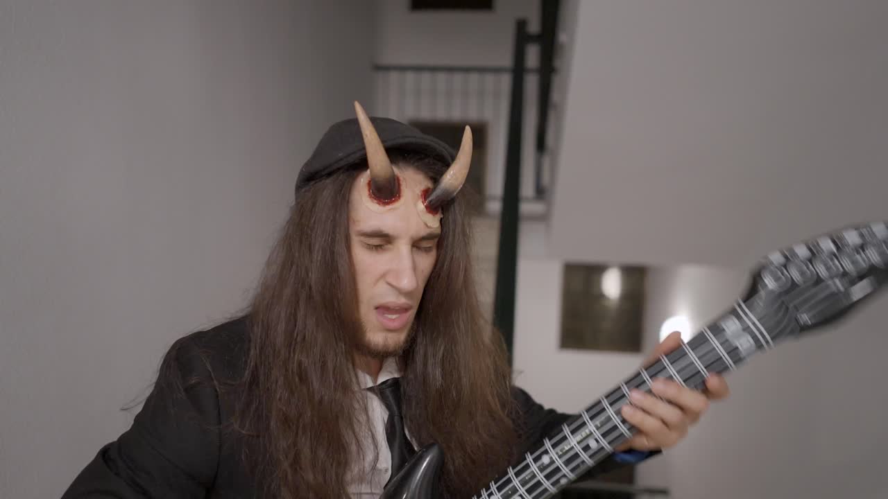 Man in Devil Costume Playing Inflatable Guitar