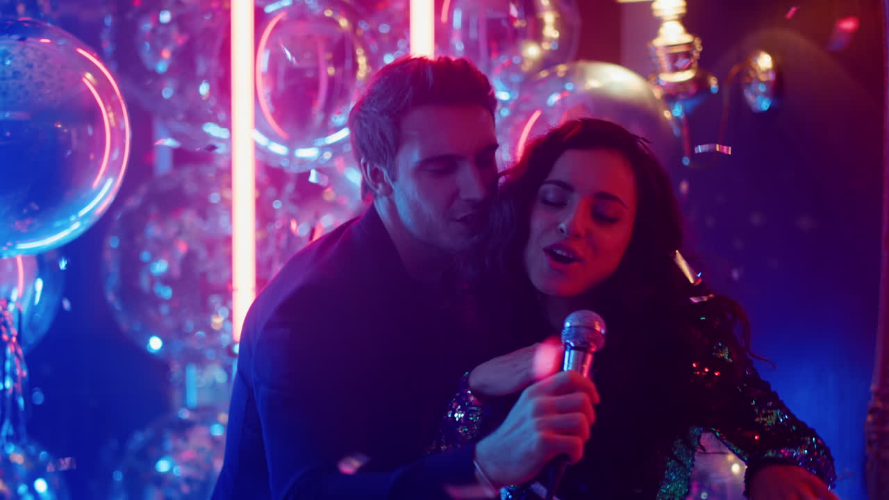 pareja sonriente interpretando una canción en una fiesta. hombre con micrófono en un club nocturno