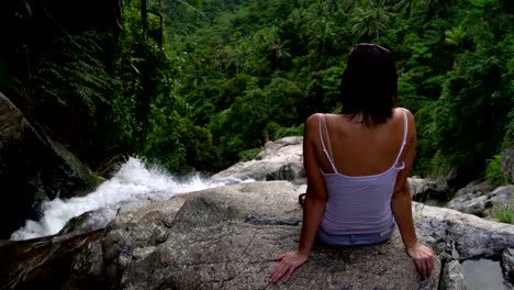 a woman sits on top of a waterfall