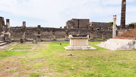 Ancient-ruins-of-Pompeii-with-weathered-columns-and-artifacts-under-a-cloudy-sky,-panning-shot