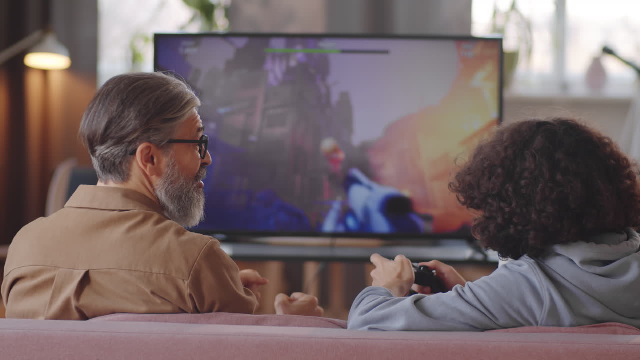 Padre e figlio che giocano a un videogioco sparatutto in TV