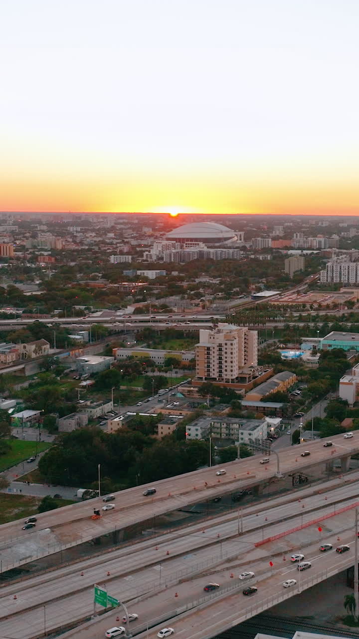 Sunset horizon over Miami city, evening cityscape with road and car traffic. Drone flight over industrial landscape. Bright sun beams on horizon. Vertical video