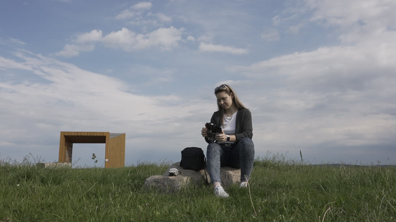 mujer joven en el parque preparando controlador y drone para vuelo, cámara lenta
