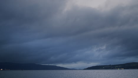 heavy blue clouds passing and boats in the distance speeding past with their lights on