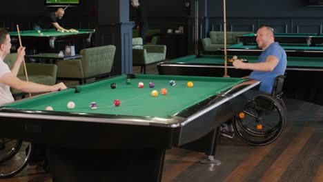 adult men with disabilities in a wheelchair play billiards in the club