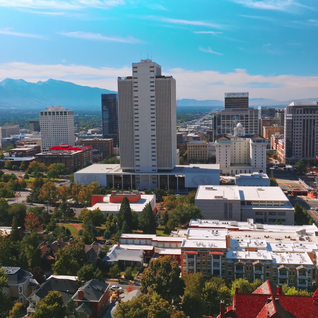 Varied architecture of sunny Salt Lake City at daytime. Stunning modern green city at backdrop of mountains. Aerial view