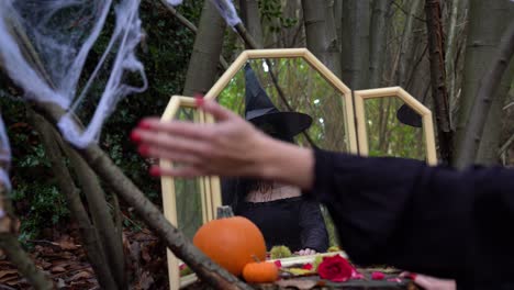 Scary-scene-with-widow-lady-changing-into-a-green-witch-in-the-woods-at-halloween,-handheld