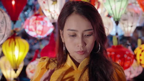 woman in yellow ao dai admiring lanterns at night in hoi an