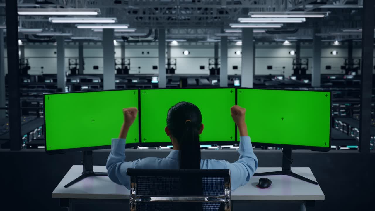 데이터 센터에서 여러 컴퓨터 모니터를 모의로 작업하는 동안 축하하는 행복한 아시아 여성의 뒷면