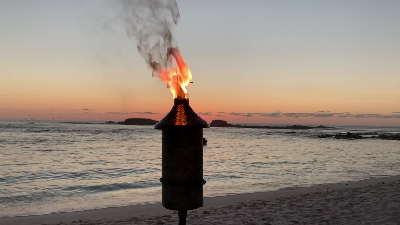 una antorcha tikki iluminando el cielo nocturno en un fondo de playa crepuscular
