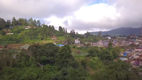 aerial drone footage of a village in berastagi. gorgeous green hills and mountains, rural village with red roofs and farmland. berastagi is one of the most beautiful villages in indonesia