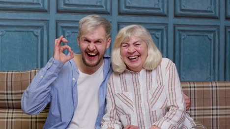 happy bonding loving generations family of senior mother and handsome adult son or grandson laughing