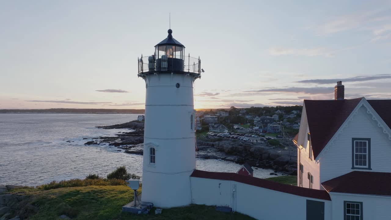 tomada aérea de un dron de york beach, maine, volando alrededor del faro de cape neddick nubble al atardecer