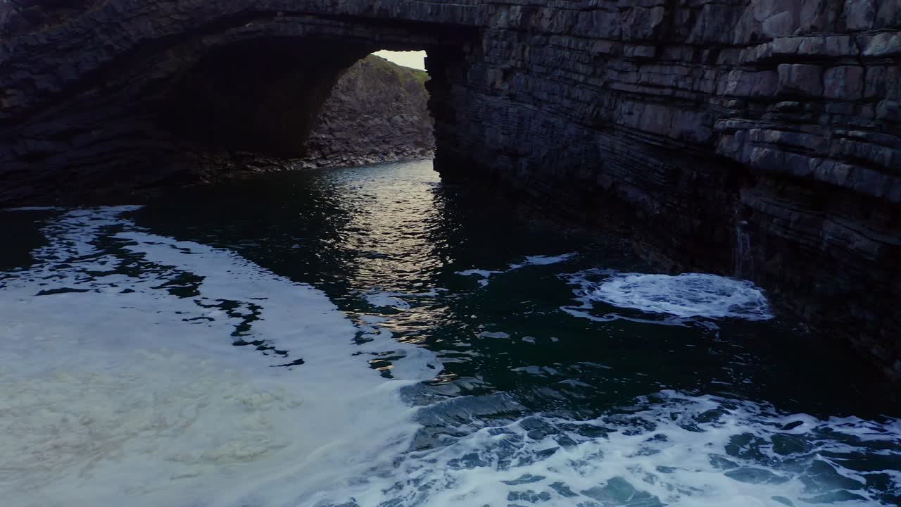 Establishing shot at the Bridges of Ross, panning wave-shaped formations to the bridge in calm evening light. Loop Head, Kilkee, Co Clare