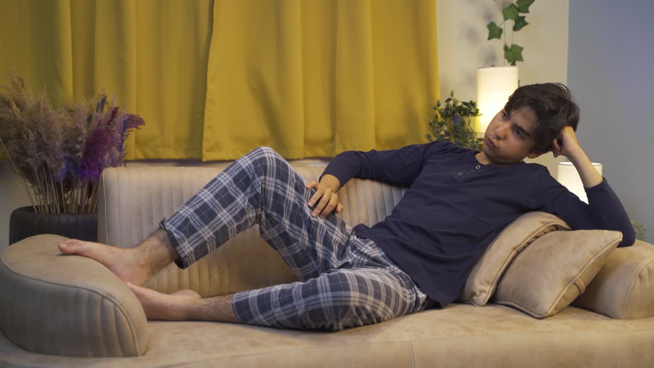 hombre deprimido y pensativo estirándose en el sofá.